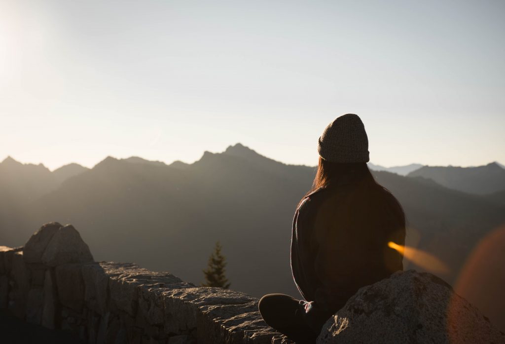 zwiazkimilosci.pl: dziewczyna w czapce medytująca wysoko w górach